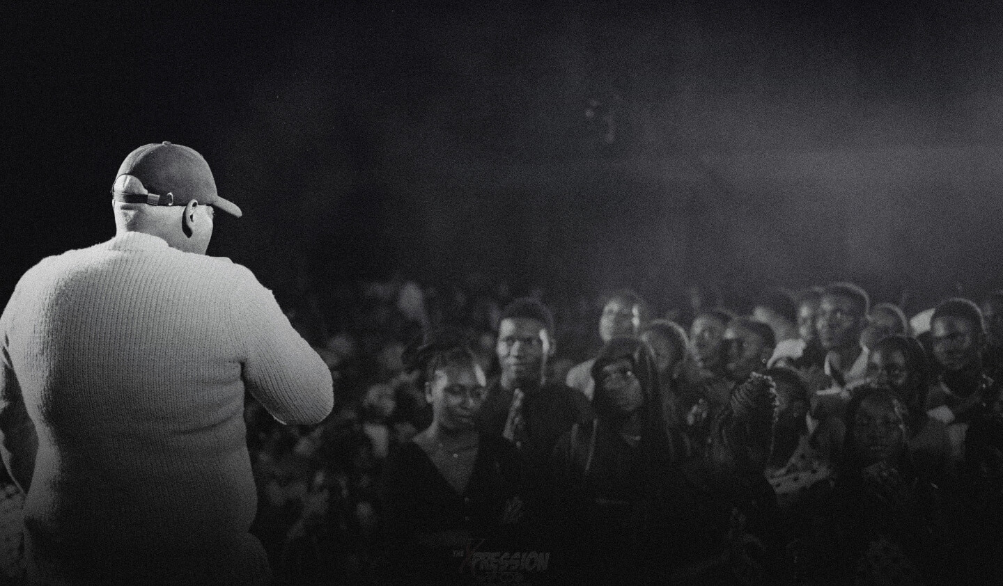 Black and white image of CDO on stage backing the camera and facing the stage